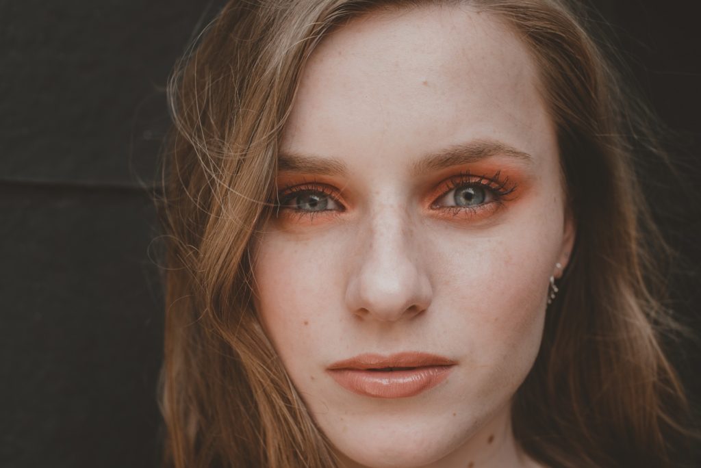 Girl with freckles close up photo orange makeup